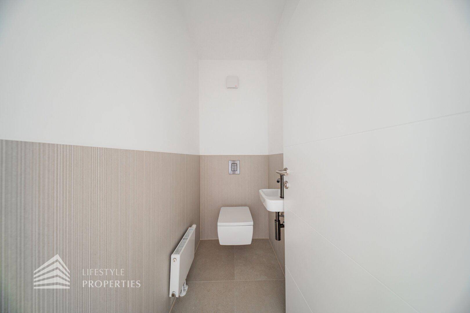 Modernes Gäste-WC mit Wand-WC, kleinem Waschbecken und stilvollen zweifarbigen Fliesen an den Wänden.
