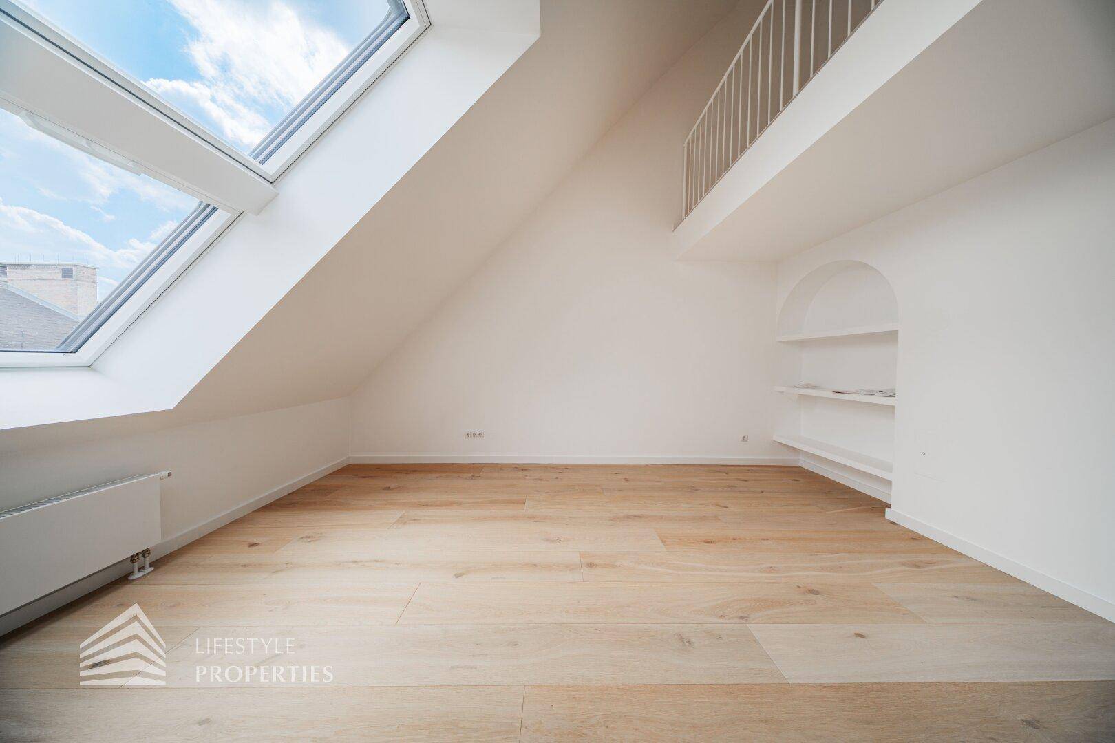 Heller Dachgeschossraum mit großem Dachfenster, eingebauter Nische und Zugang zur oberen Galerie.