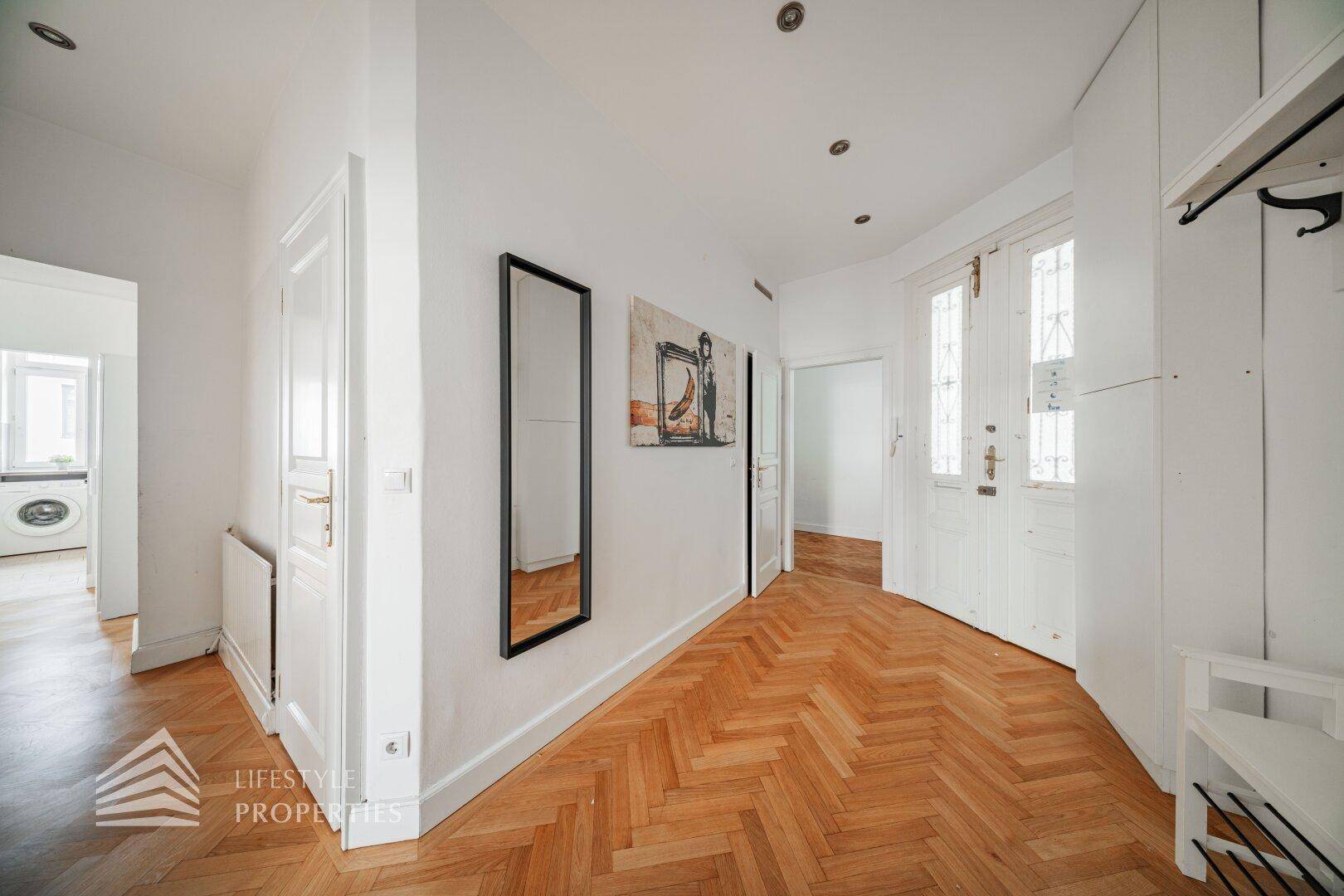 Eingangsbereich mit Fischgrätparkett, Garderobe und viel Tageslicht durch die Eingangstür.