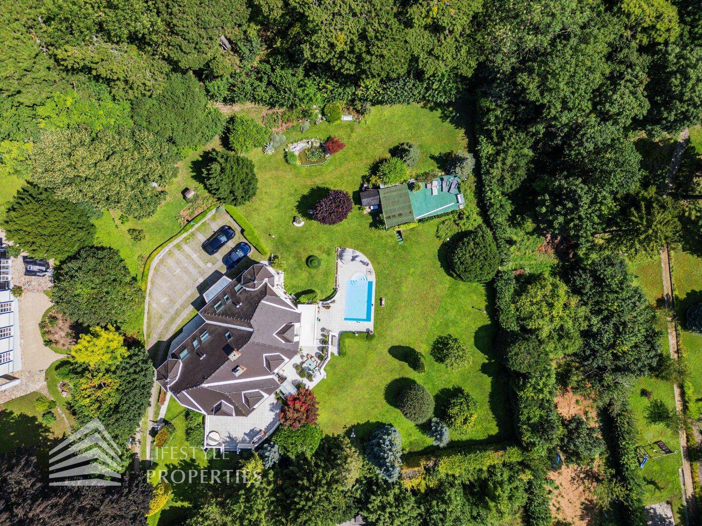 Weitläufige Luftaufnahme des Anwesens mit Villa, großem Garten, Pool und umgebender Natur.