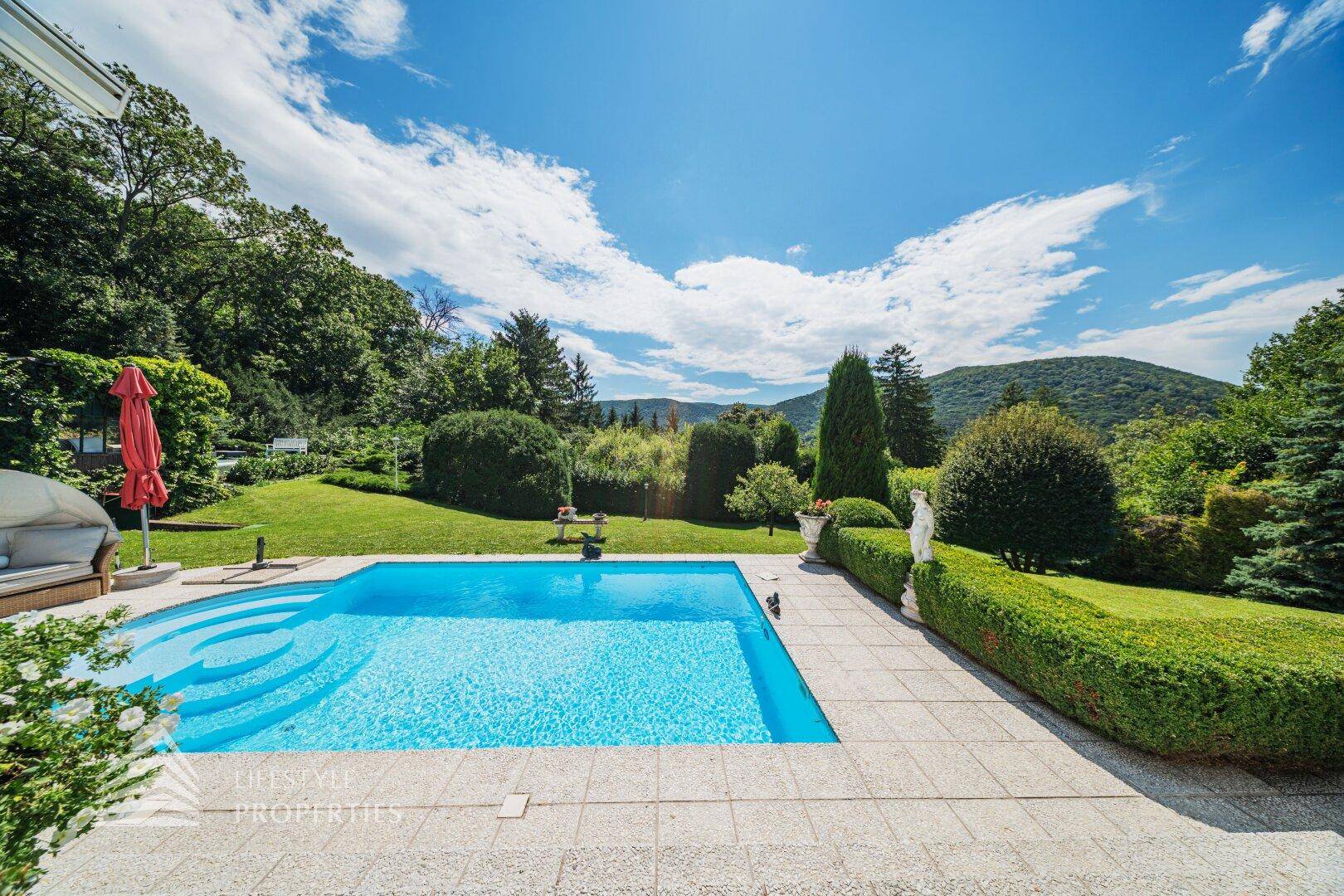 Der einladende Poolbereich mit Sonnenterrasse und weitem Blick auf die grüne Hügellandschaft.