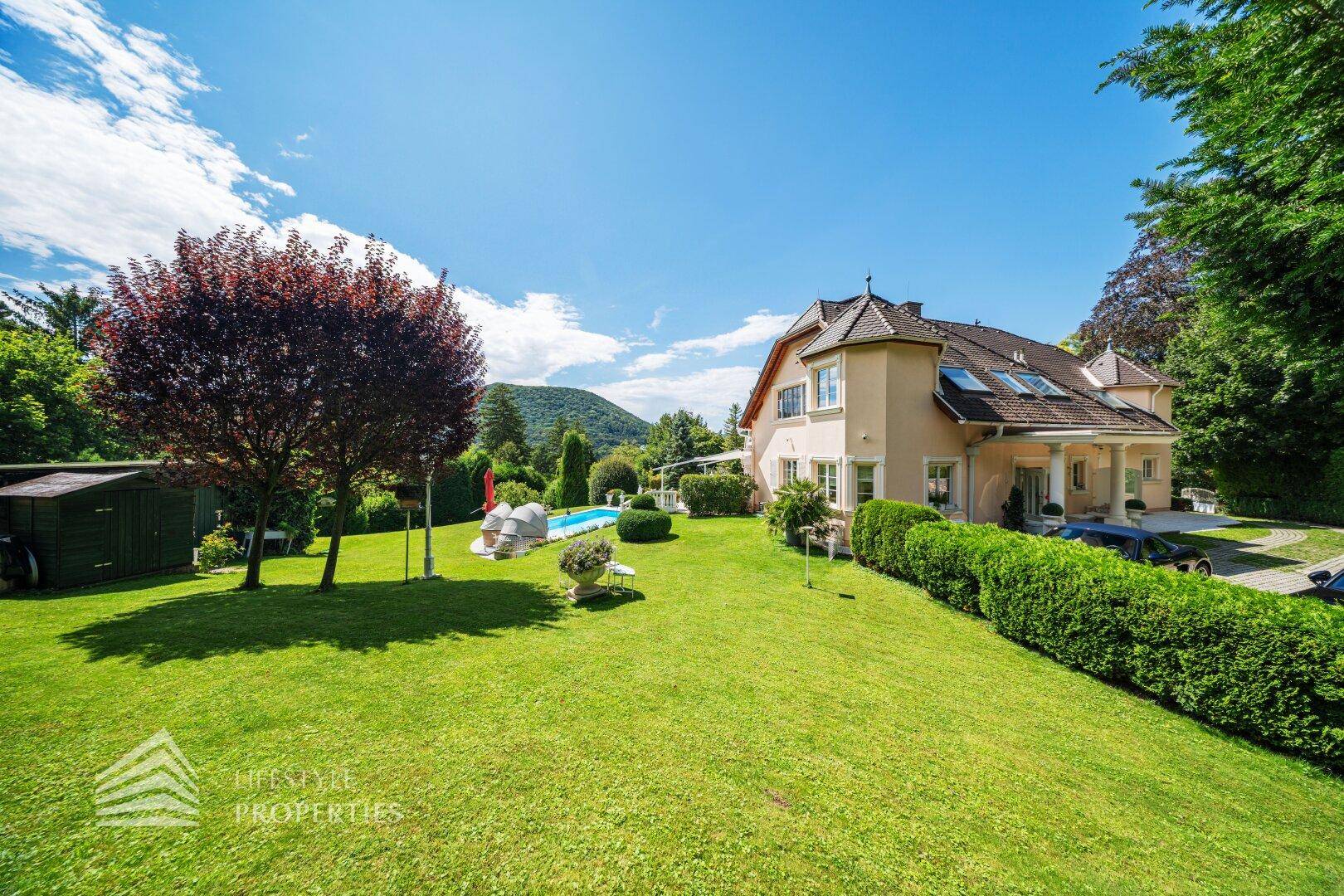 Der weitläufige Rasenbereich des Gartens mit Blick auf die Villa und den Poolbereich.