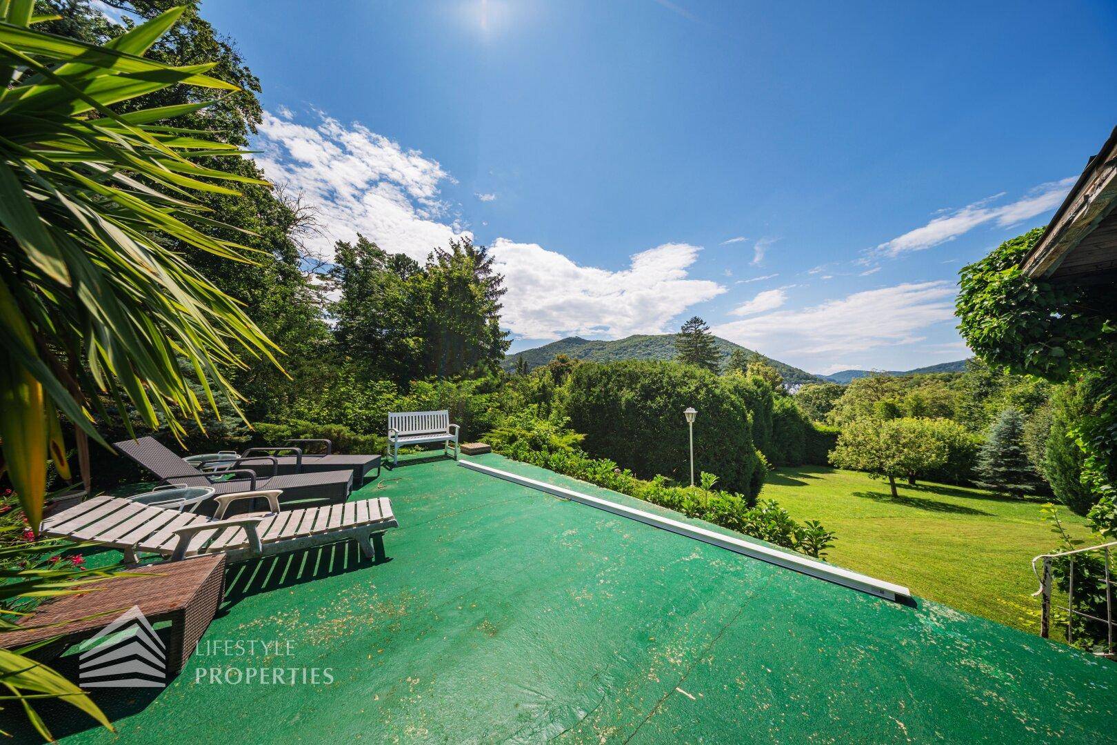 Grüne Dachterrasse mit Liegestühlen und weitem Blick über die bewaldete Landschaft.