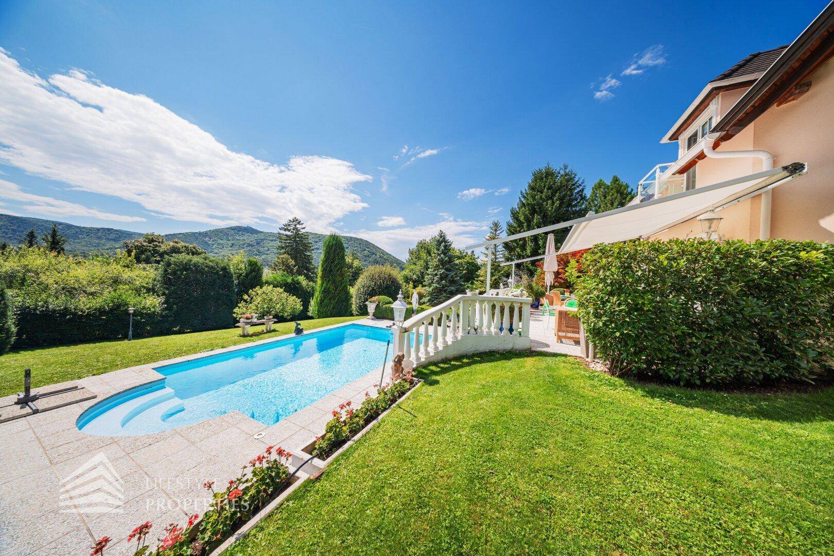 Der gepflegte Garten mit Pool, Terrasse und Blick auf die umliegende grüne Landschaft.