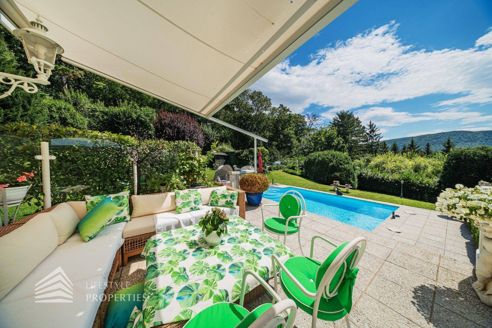 Eine großzügige Terrasse mit Pool, bequemen Sitzgelegenheiten und weitem Blick ins Grüne.
