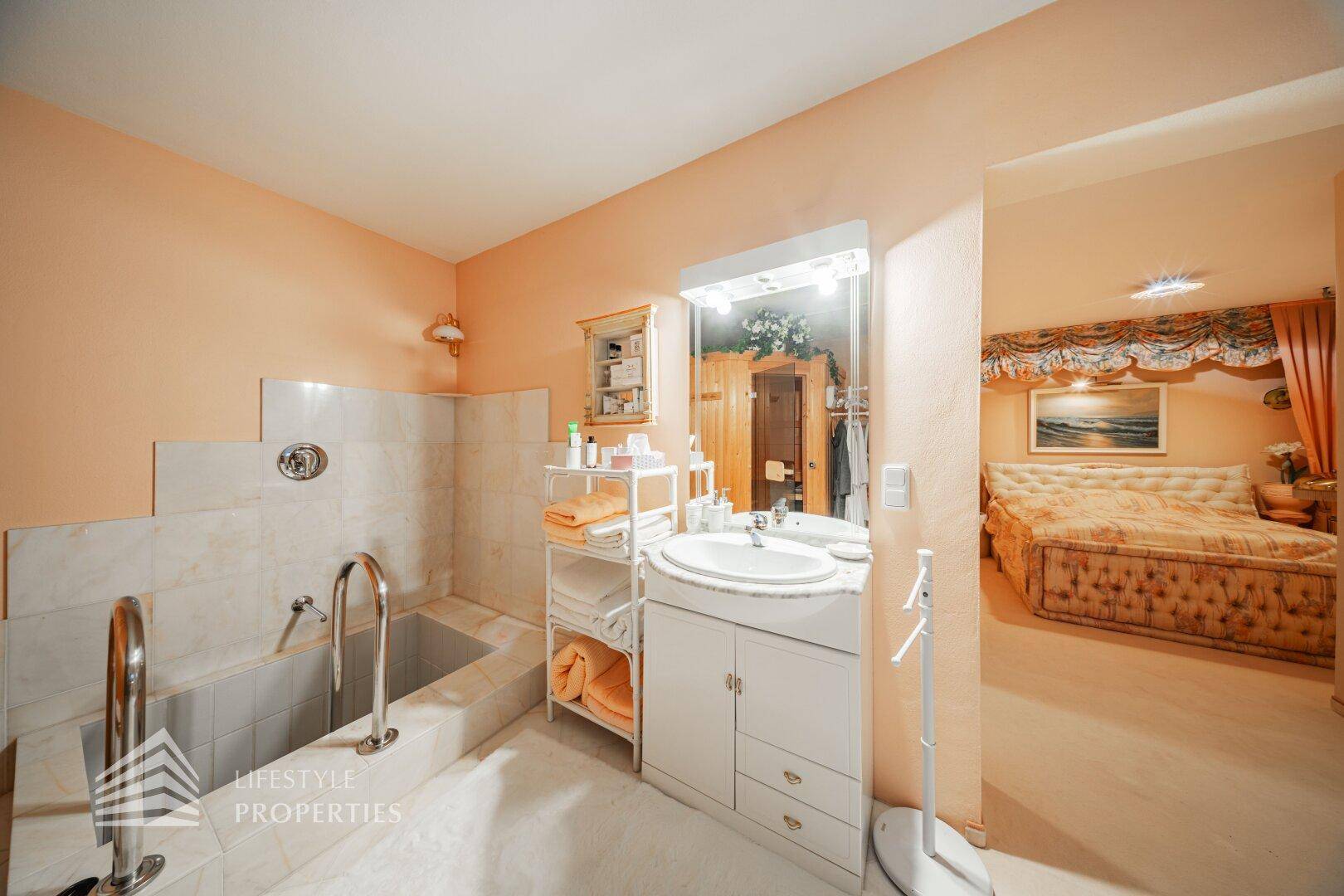 Badezimmer mit eingebauter Badewanne und Einzelwaschbecken, direkt an das Schlafzimmer angrenzend.