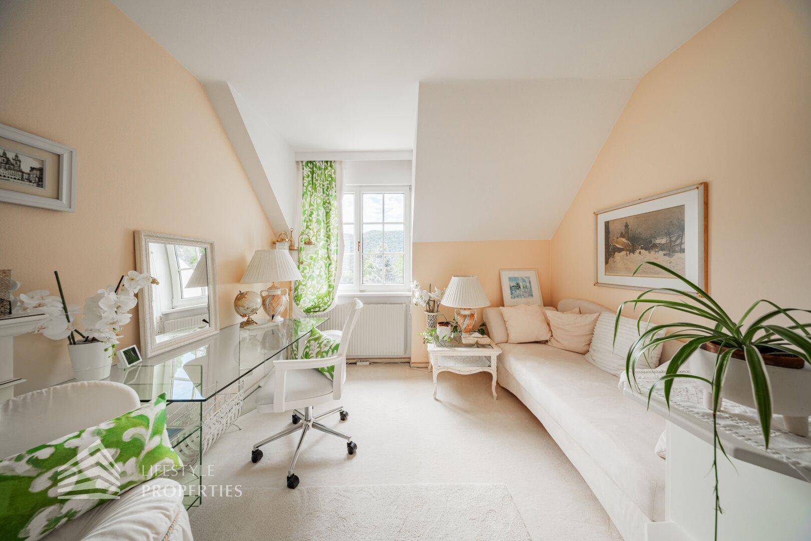 Helles Schlafzimmer im Dachgeschoss mit Tagesbett, Schreibtisch und Blick ins Grüne.