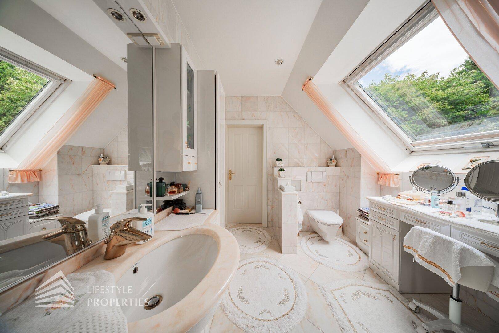 Helles Badezimmer mit Waschbecken, Toilette und großen Dachfenstern für viel Tageslicht.