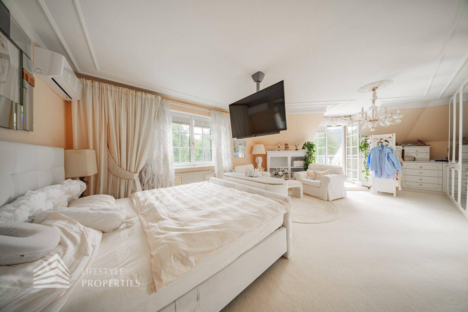 Geräumiges Schlafzimmer mit großem Bett, Fernseher und Zugang zu einem Balkon oder Terrasse.