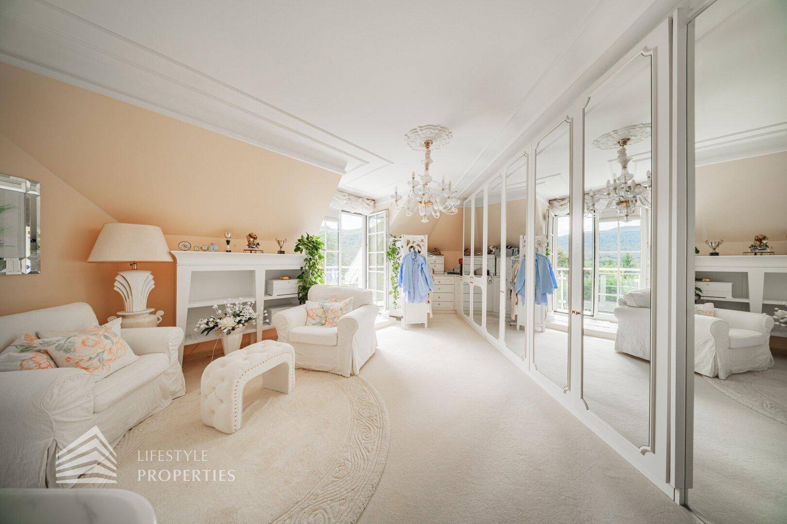 Geräumiges Ankleidezimmer mit Spiegelschränken, Sitzgelegenheiten und Zugang zum Balkon.
