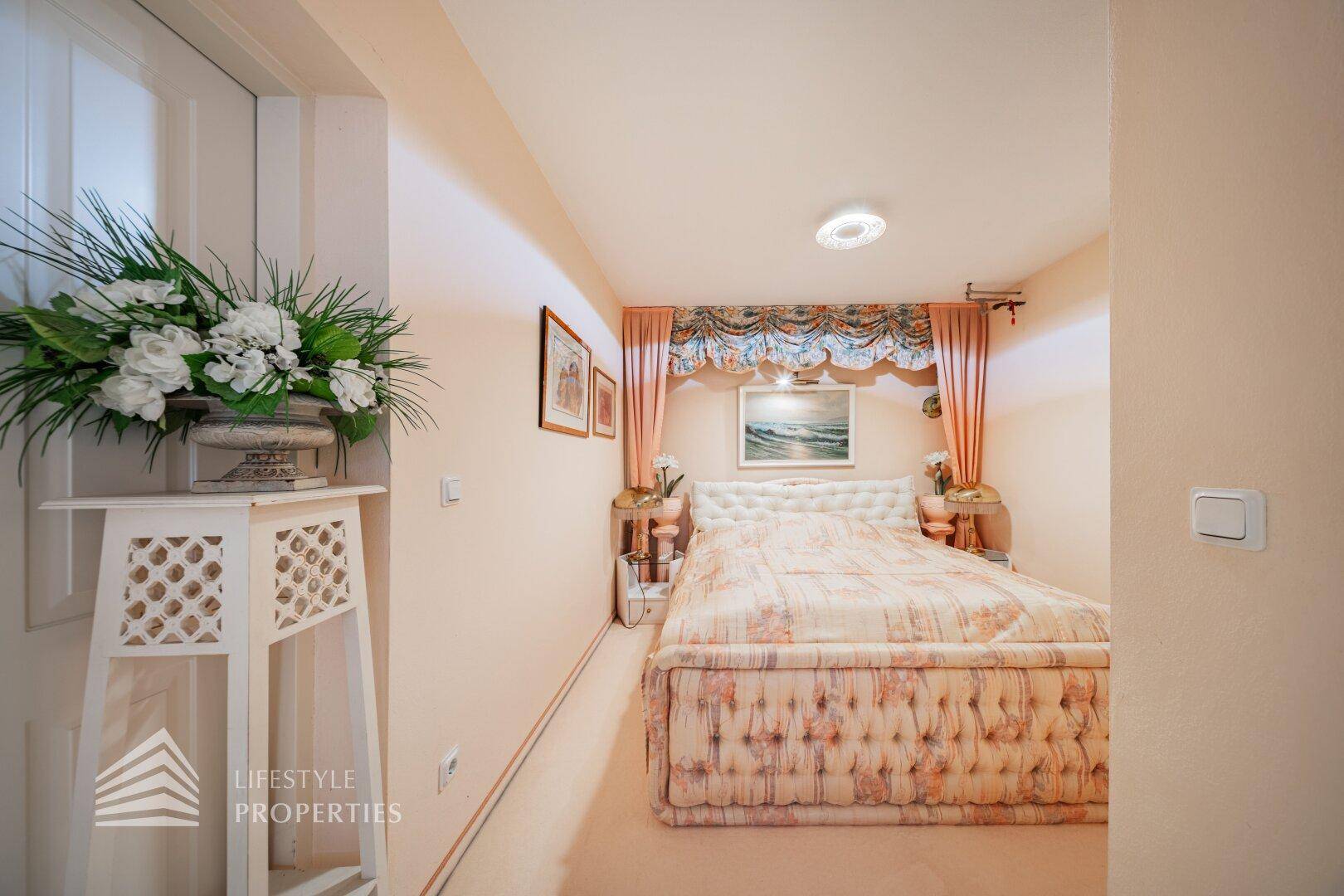 Gemütliches Schlafzimmer mit großem Bett, Vorhängen und floraler Dekoration.