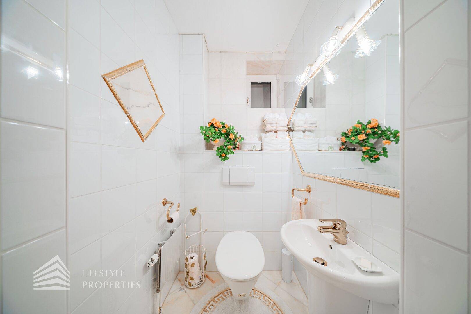 Kleines Gäste-WC mit weißen Fliesen, Toilette und Waschbecken.
