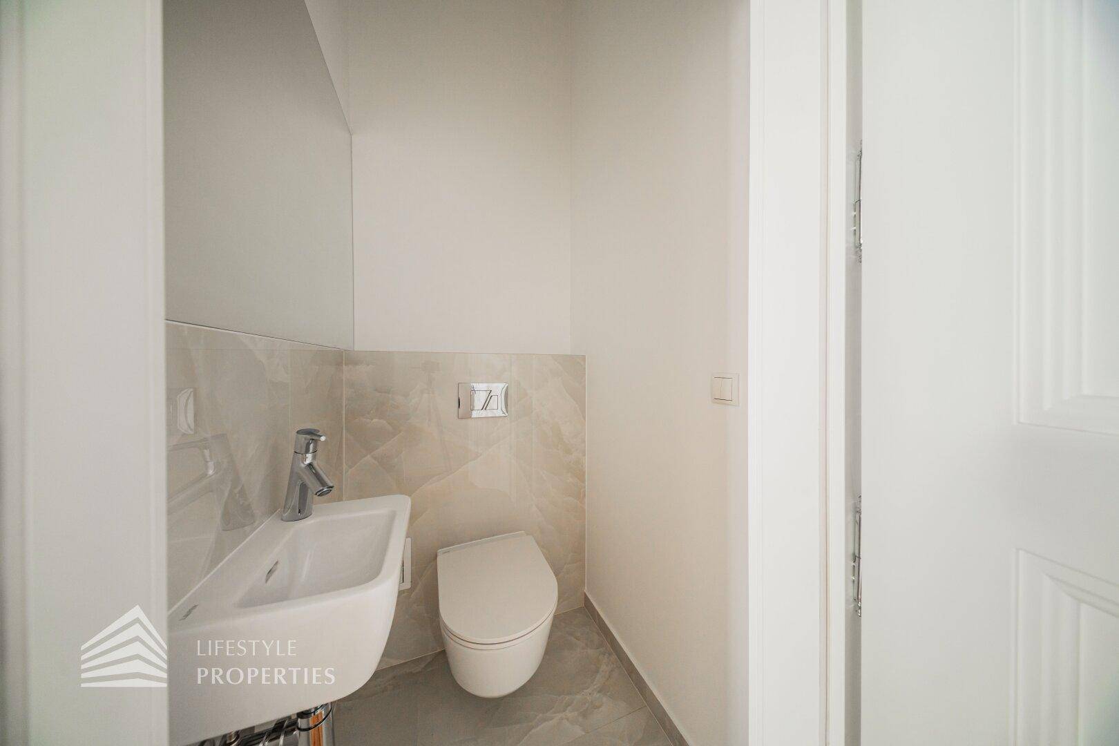 Kleines Gäste-WC mit wandhängender Toilette und modernem Waschbecken.