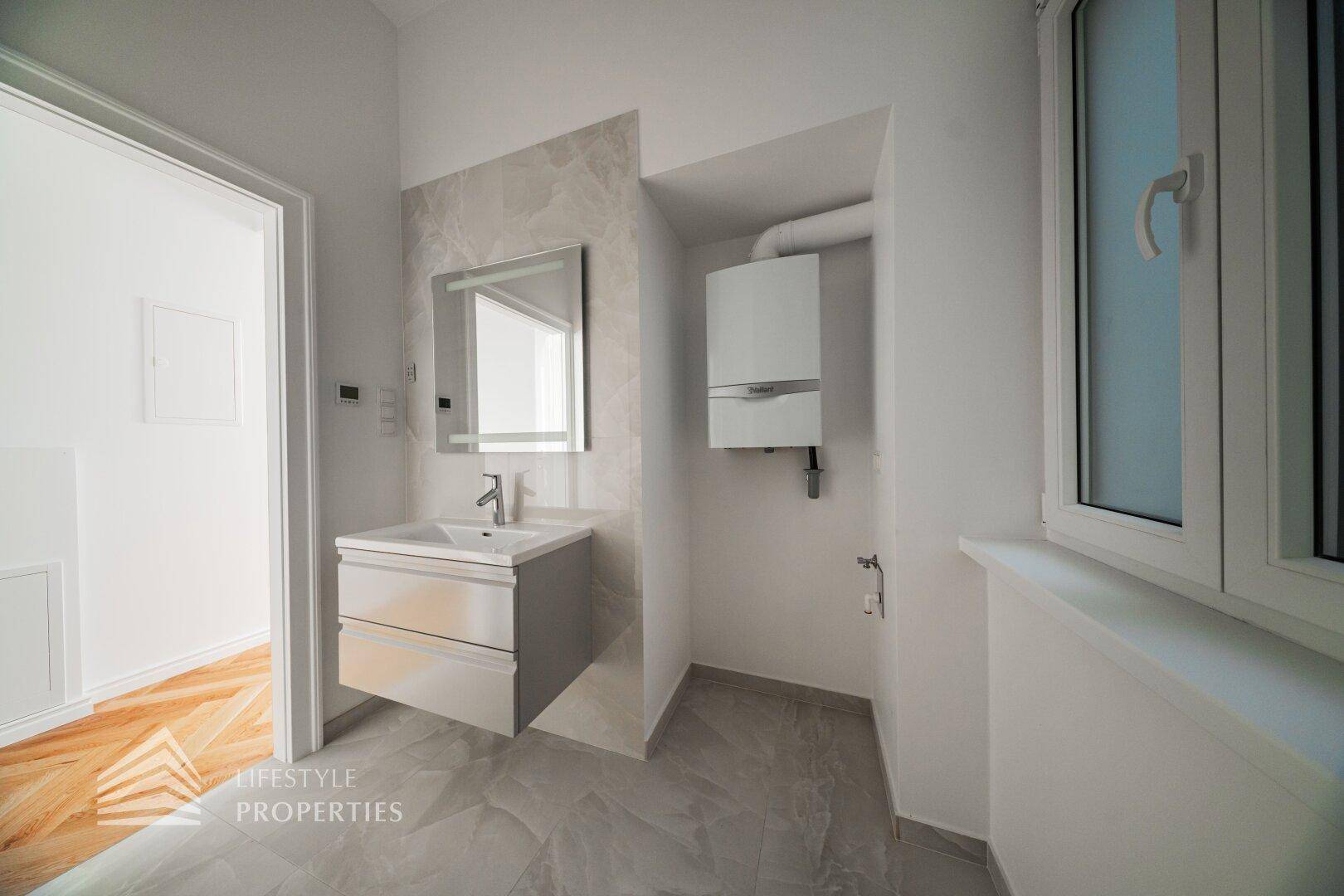 Modernes Badezimmer mit Einzelwaschbecken, Spiegel und Gastherme an der Wand.