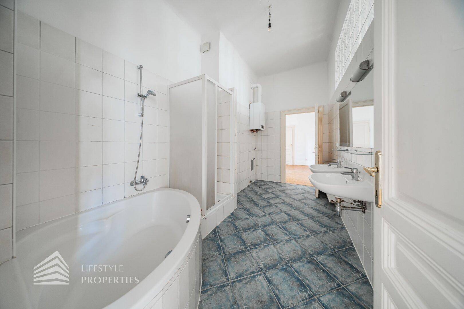 Badezimmer mit Badewanne, Duschkabine und zwei Waschbecken, bereit für eine Modernisierung.