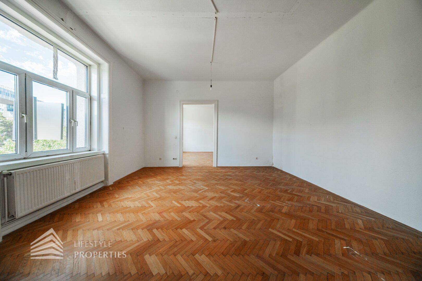 Helles, leeres Zimmer mit Fischgrätparkett und großen Fenstern, ideal für neue Einrichtungsideen.