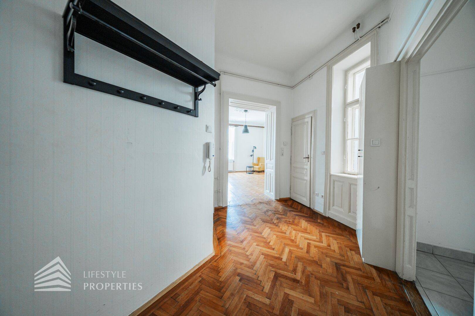Heller Flur mit Fischgrätparkett und Zugang zu weiteren Räumen der Wohnung.