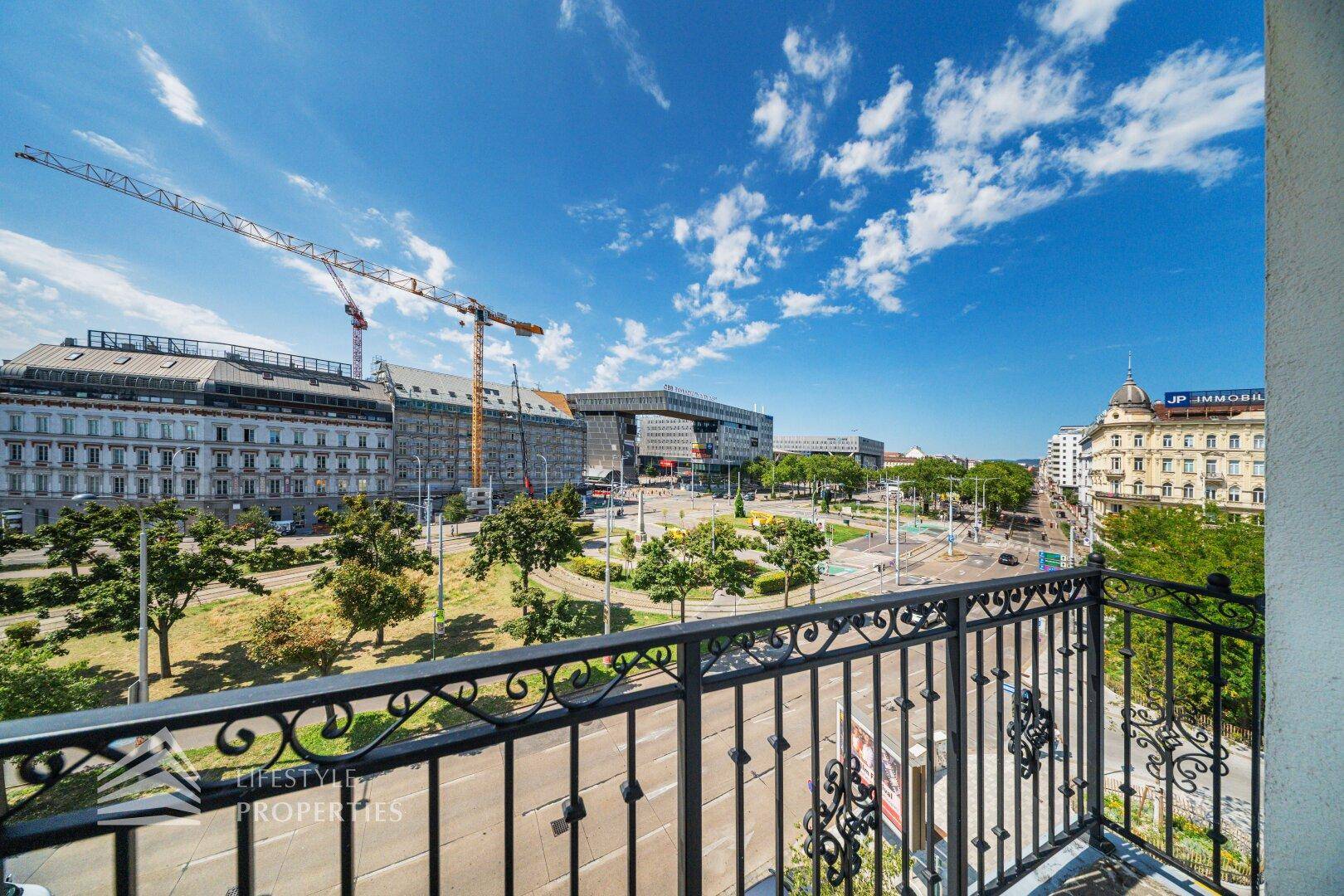 Balkon mit schmiedeeisernem Geländer und weitem Blick über die Stadt und den Verkehr.