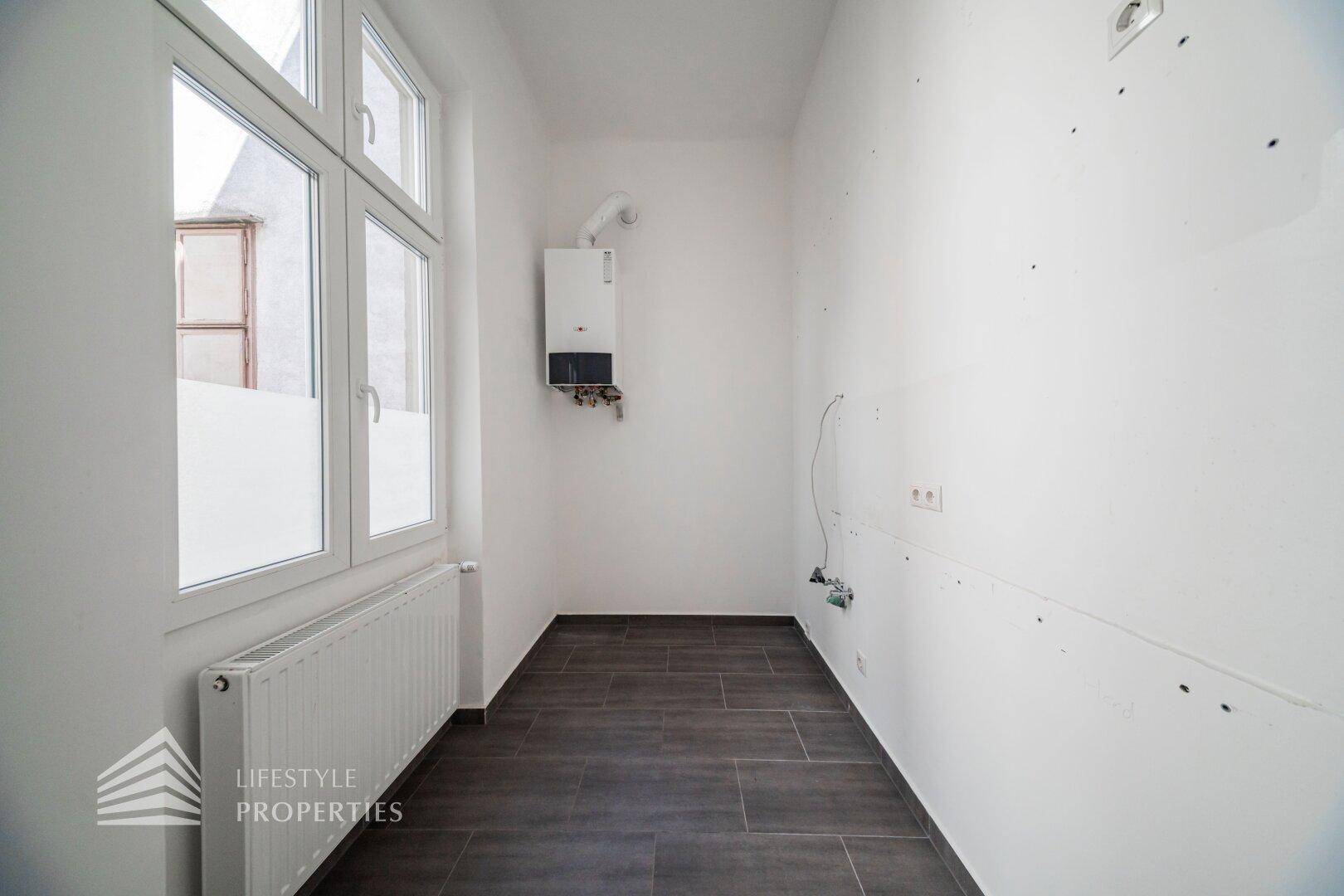 Heller Hauswirtschaftsraum mit Fenster, Heizkörper und Warmwasserbereiter, ideal für Waschmaschine.