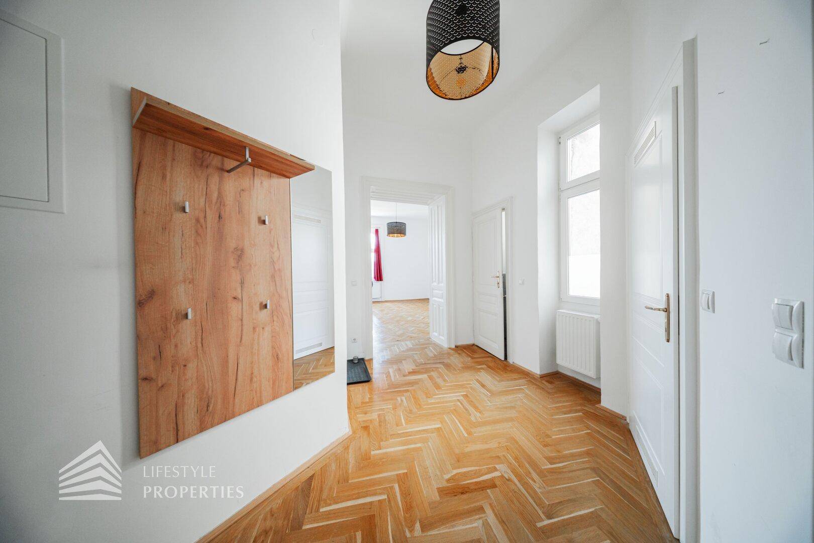 Einladender Eingangsbereich mit Fischgrätparkett, Garderobe und viel Tageslicht.