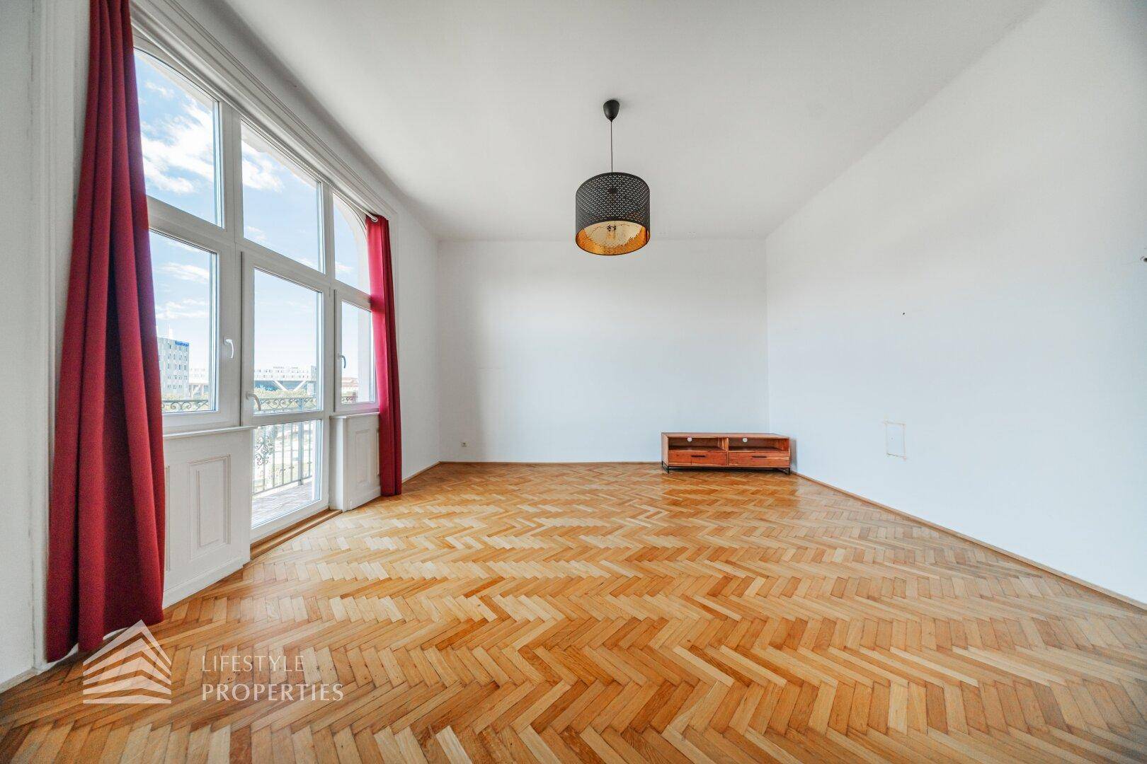 Lichtdurchflutetes Wohnzimmer mit großen Fenstern und Zugang zu einem französischen Balkon.