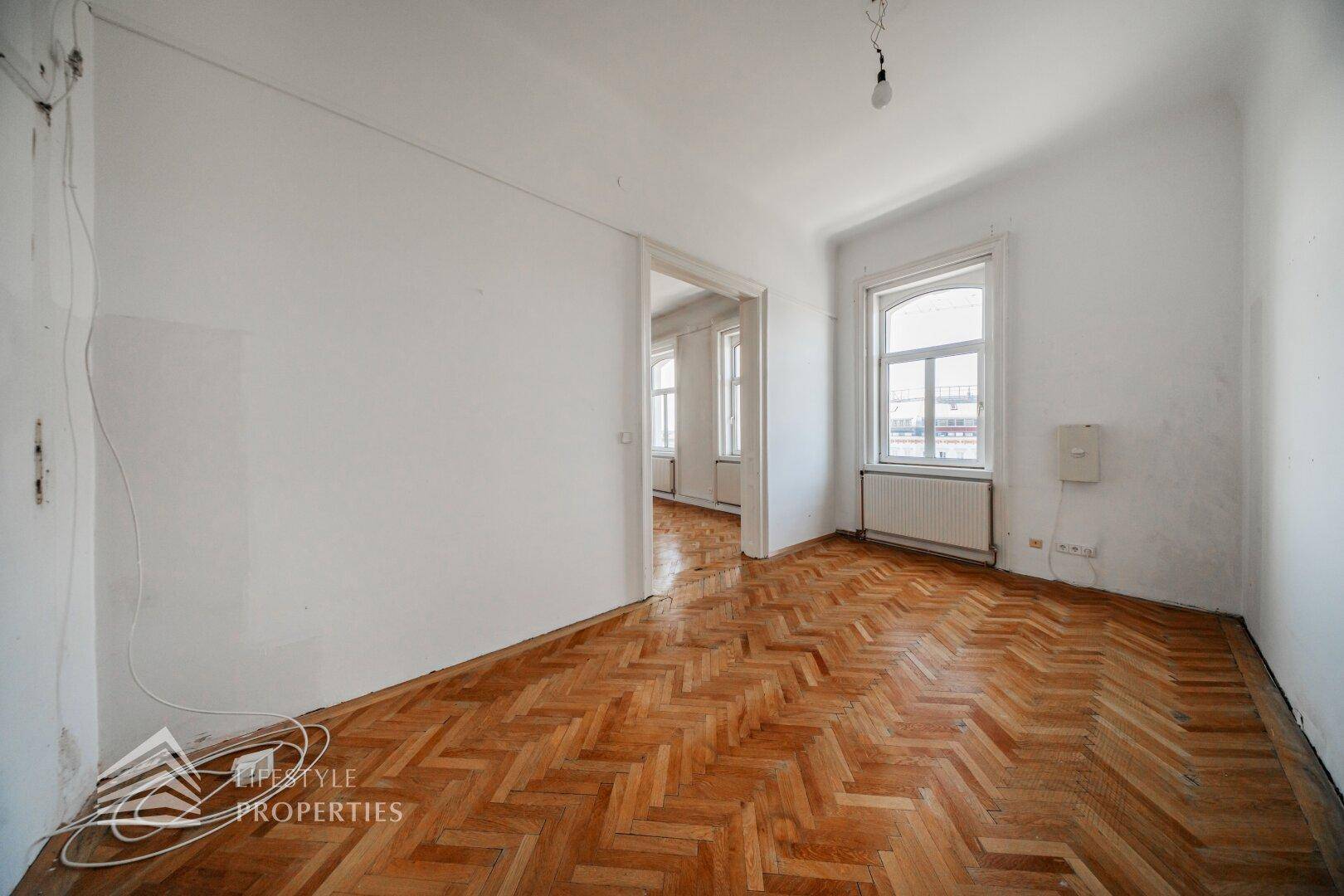 Leerer Raum mit Fischgrätparkett und Fenster, ideal für Schlafzimmer oder Arbeitszimmer.