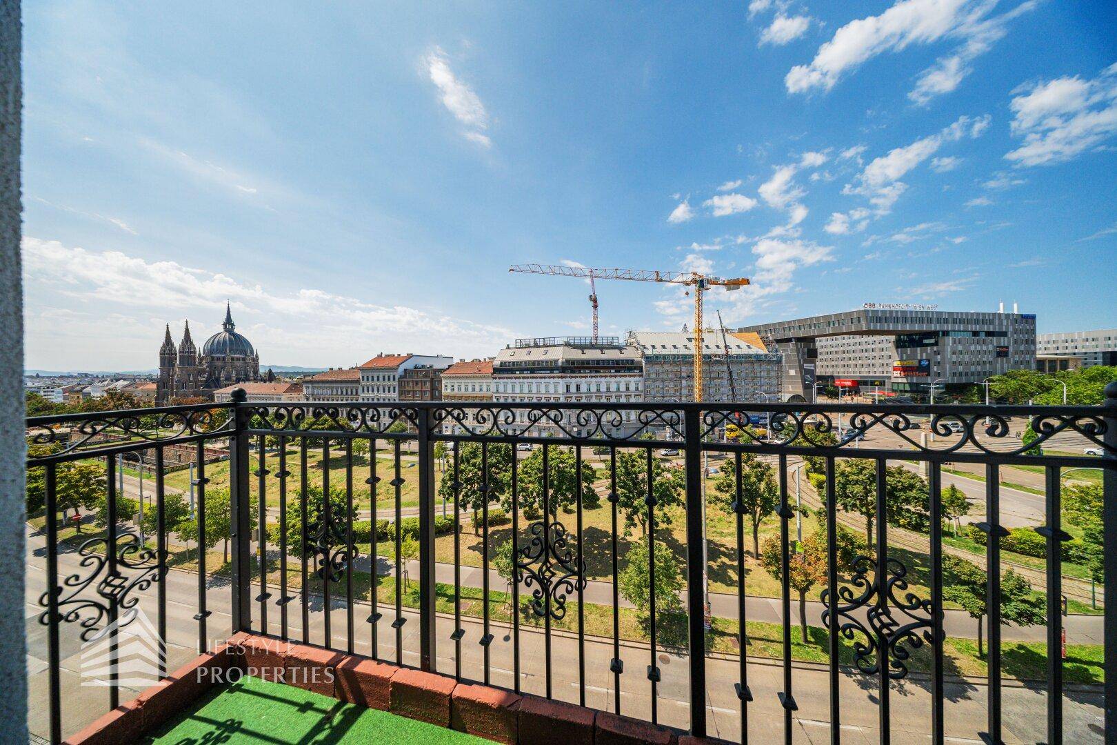 Balkon mit schmiedeeisernem Geländer und Blick auf die Stadt und historische Gebäude.