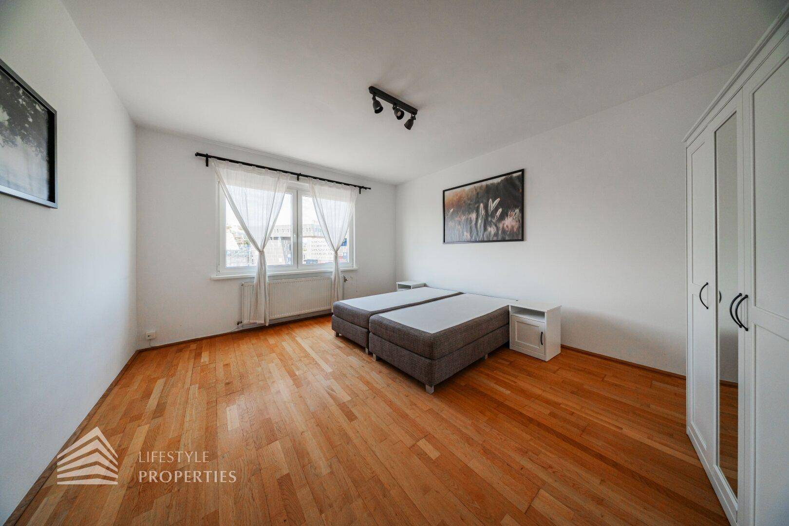 Helles Schlafzimmer mit Holzboden, zwei Einzelbetten und einem weißen Kleiderschrank.