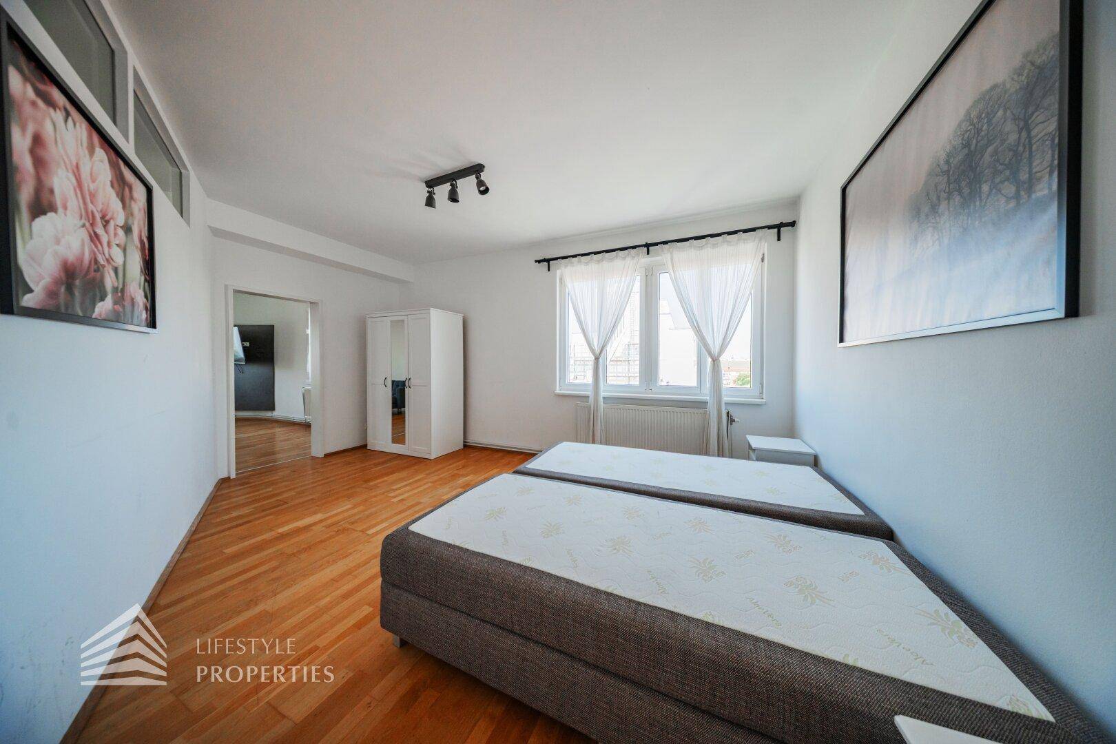 Helles Schlafzimmer mit Holzboden, zwei Betten und einem Kleiderschrank, der viel Stauraum bietet.