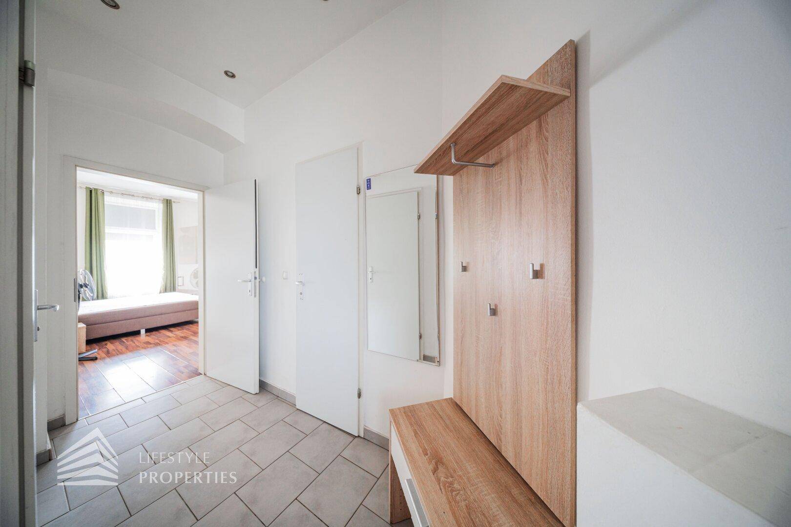 Heller Flur mit Fliesenboden, Garderobe und Zugang zu weiteren Zimmern.