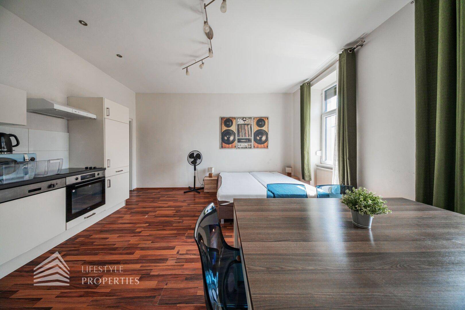 Moderne Küchenzeile mit weißen Schränken, Kochfeld und Essbereich im offenen Wohnraum.
