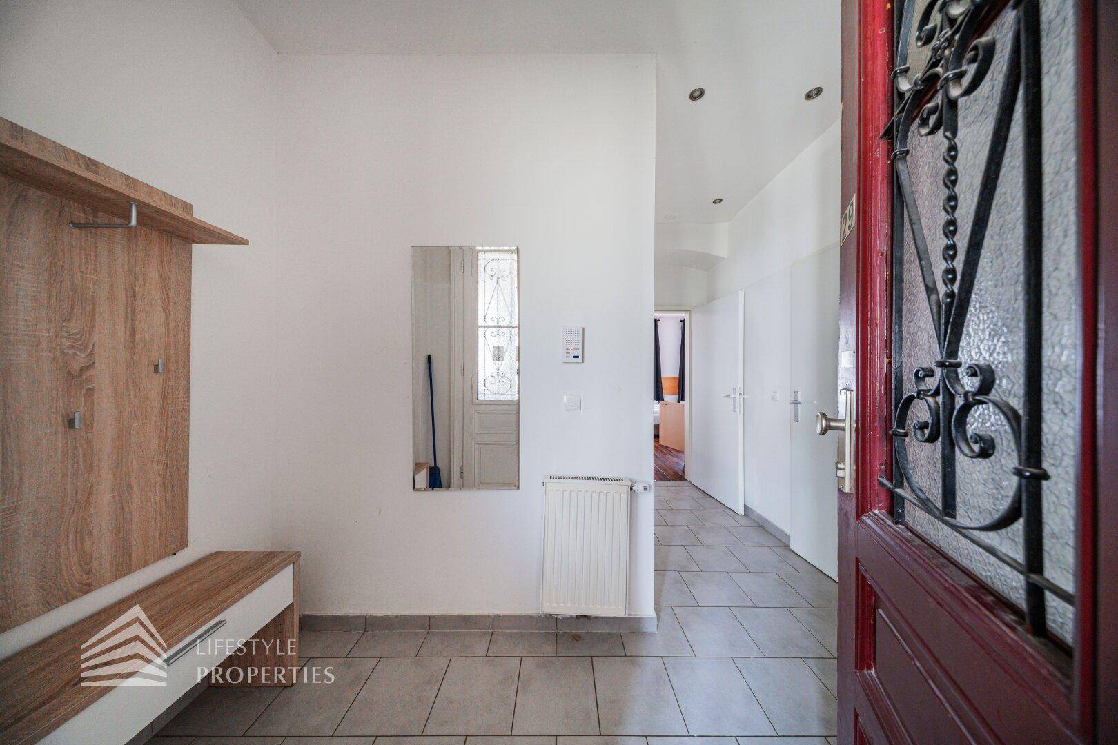 Eingangsbereich mit Garderobe, Spiegel und Fliesenboden, führt zu den weiteren Räumen.