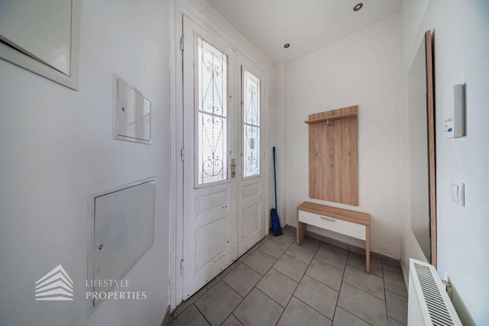 Heller Flur mit weißer Eingangstür und Garderobe, ausgestattet mit praktischem Fliesenboden.