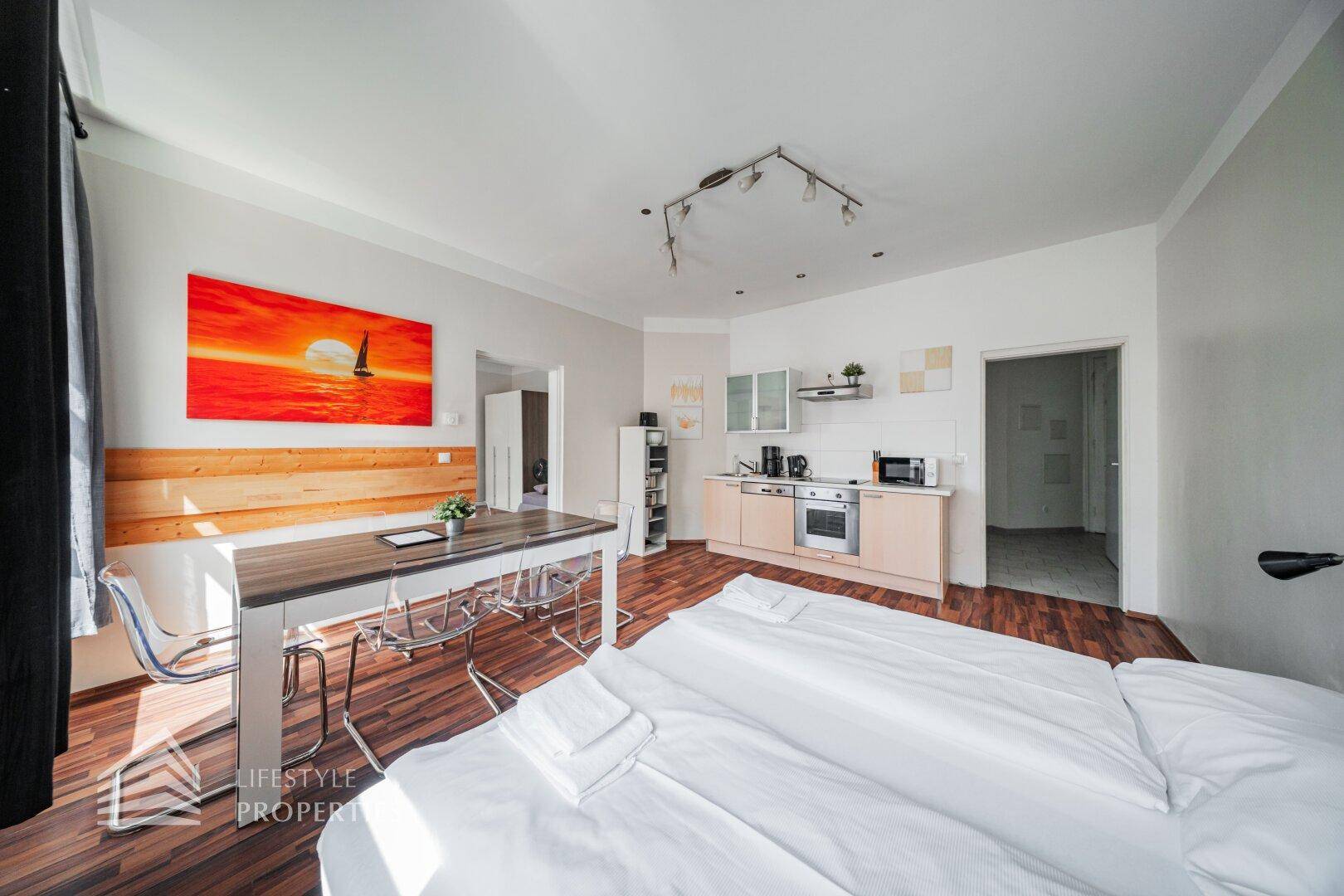 Offenes Studio-Apartment mit Schlafbereich, Essplatz und kleiner Küche, hell und funktional eingerichtet.