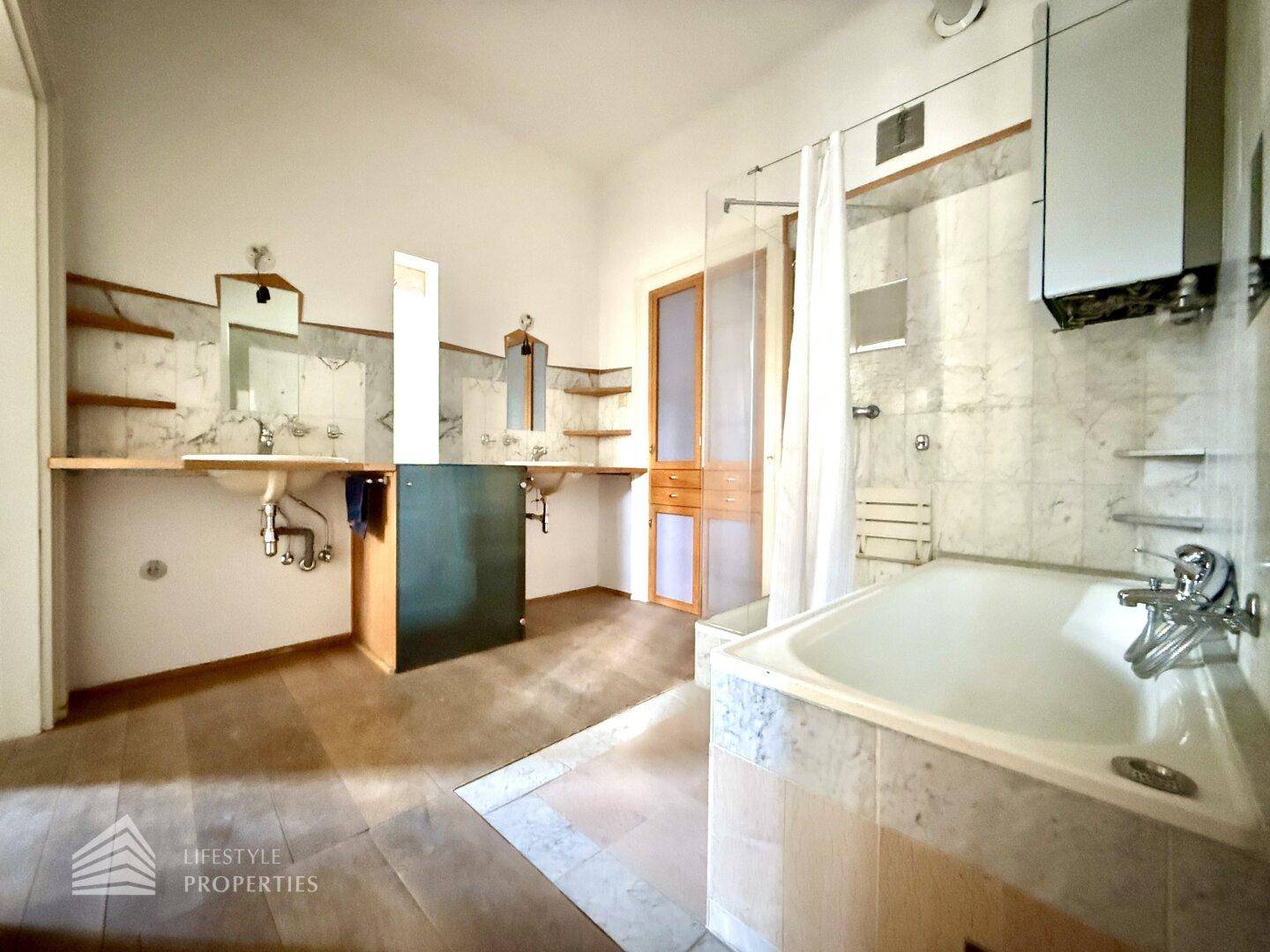 Helles Badezimmer mit Doppelwaschbecken, Duschbereich und Badewanne, ausgestattet mit Marmoroberflächen.