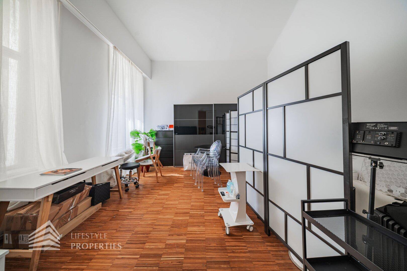 Langer Büroraum mit Schreibtisch am Fenster, einem Raumteiler und Stauraum, ideal für konzentriertes Arbeiten.