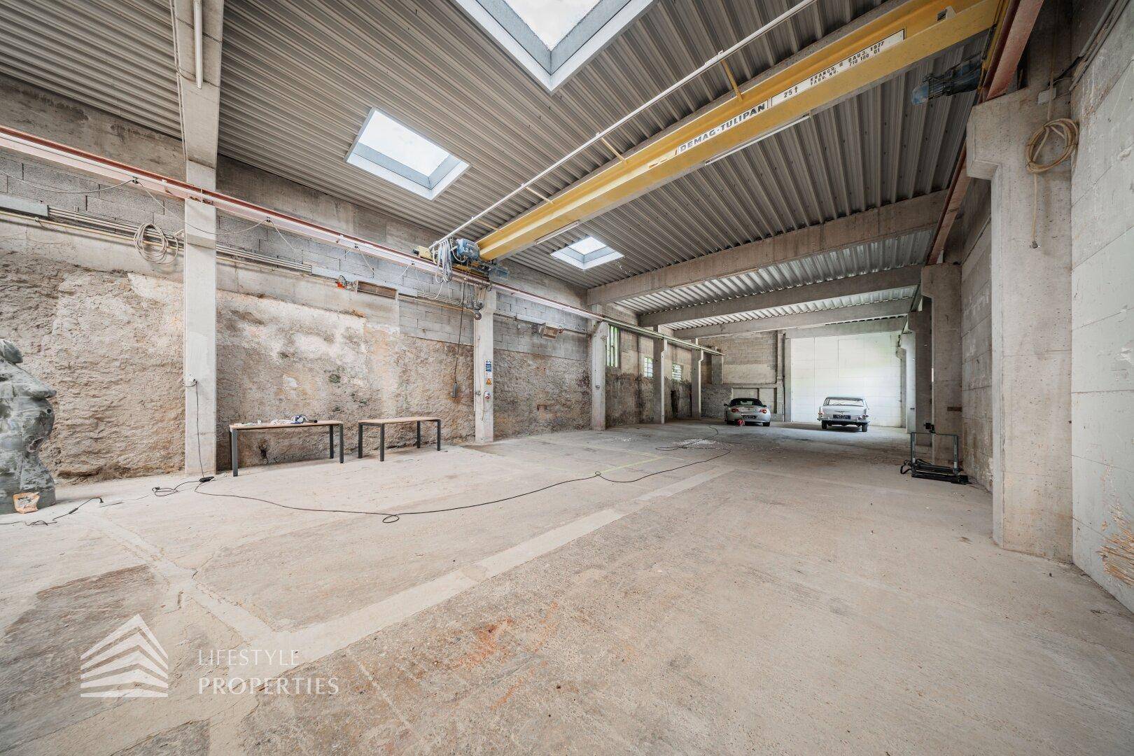 Industrielle Lagerhalle mit Betonboden, hohen Decken und einem Kran, ideal für schwere Lasten.