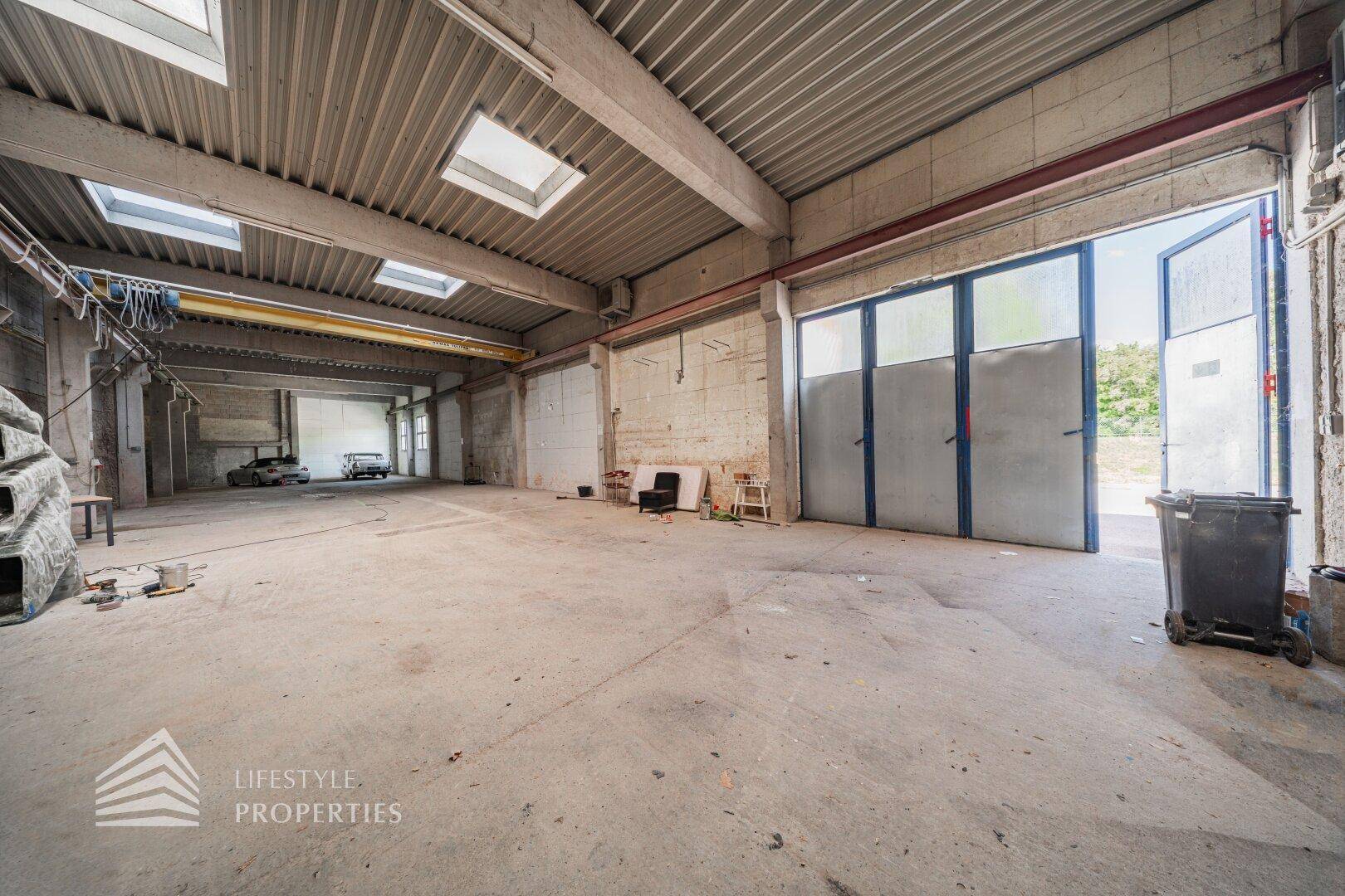 Geräumige Lagerhalle mit Betonboden, hohen Decken und Oberlichtern, bereit für gewerbliche Nutzung.