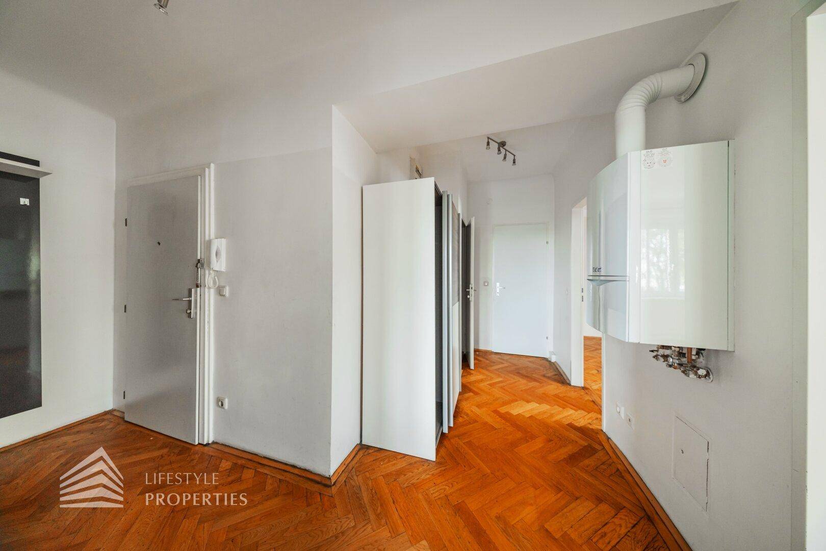 Eingangsbereich mit Fischgrätparkett, praktischer Garderobe und sichtbarer Heiztherme an der Wand.