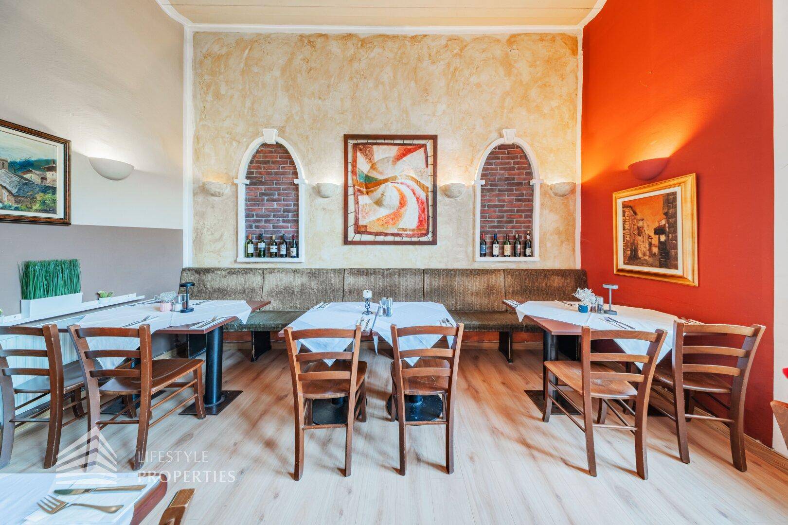 Gemütlicher Restaurantbereich mit rustikalen Ziegelnischen, bequemen Sitzbänken und Holzboden.