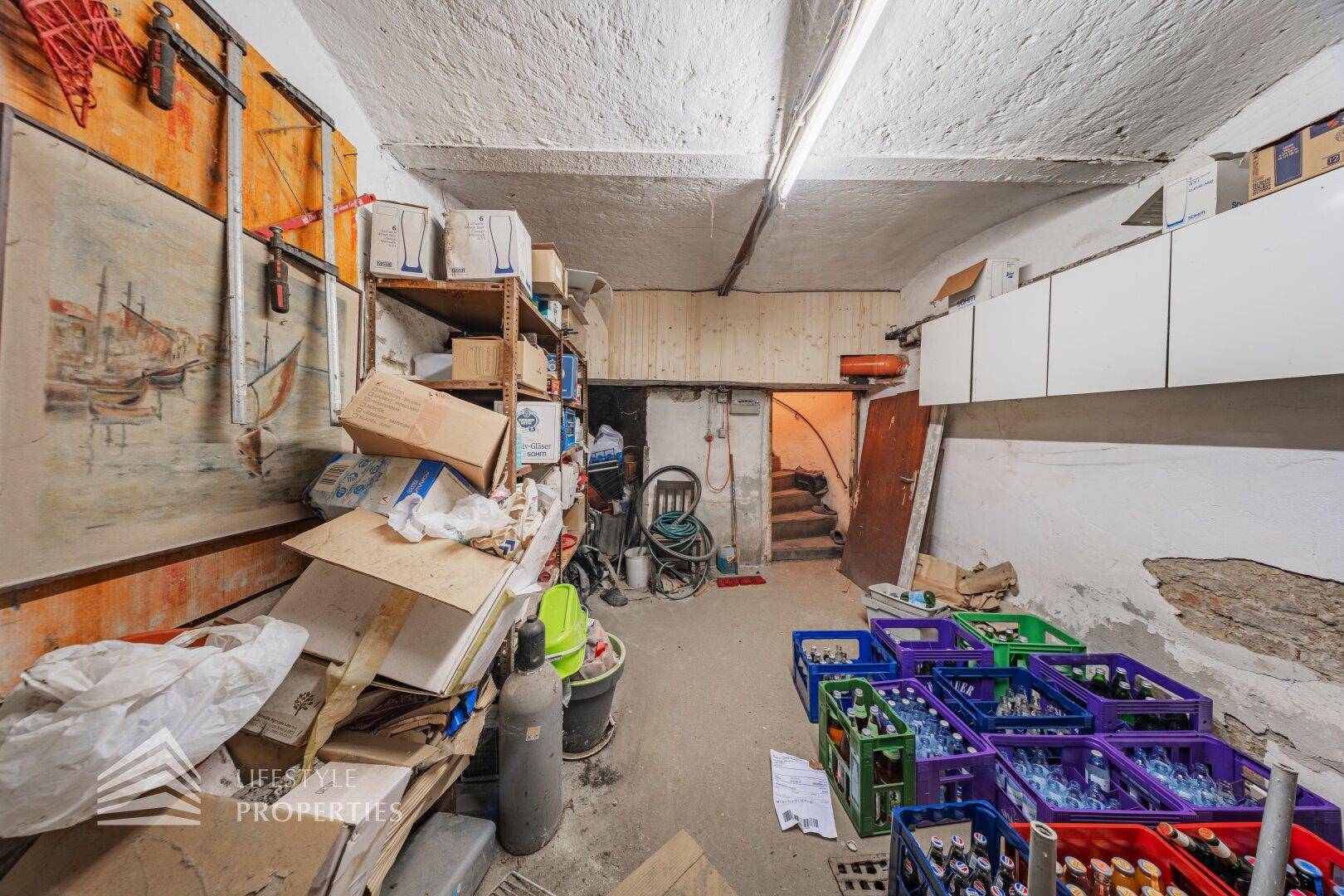 Unaufgeräumter Lagerraum im Keller mit Regalen, Getränkekisten und rauen Wänden, funktional.