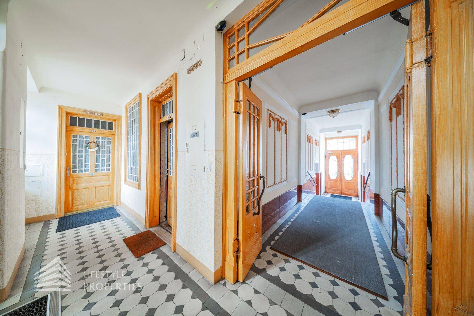 Historischer Hausflur mit gemusterten Fliesen, Holztüren und traditioneller Architektur, einladend.