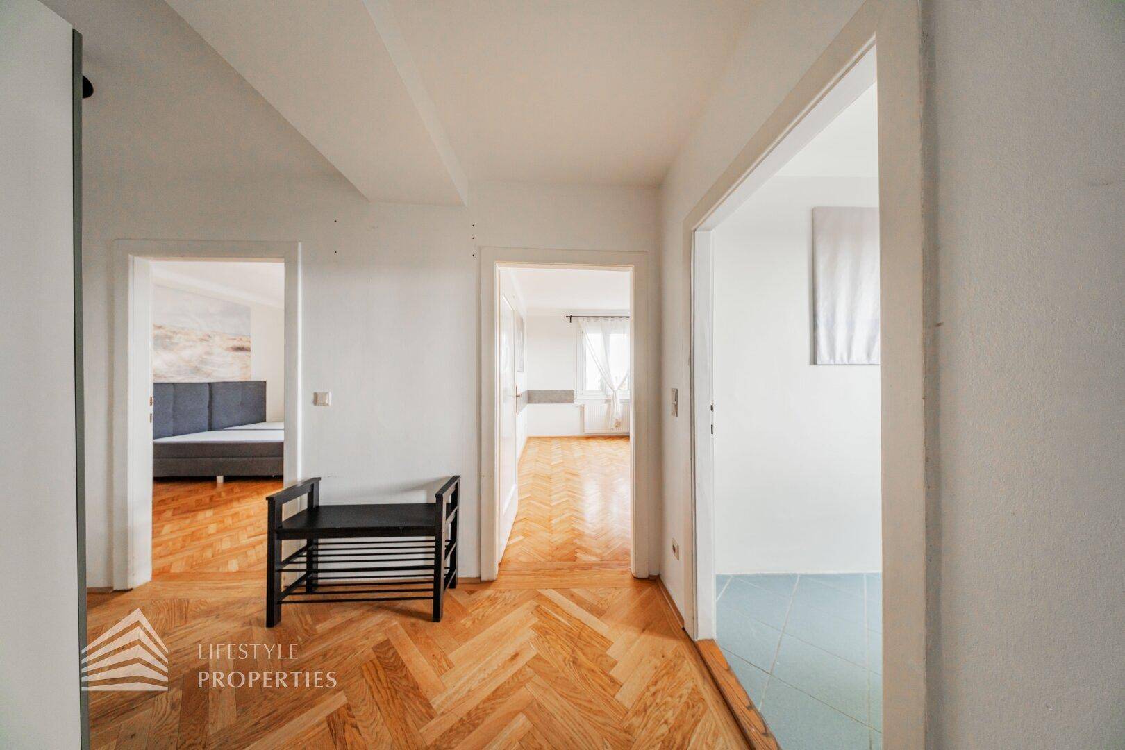 Heller Flur mit Fischgrätparkett, der zu verschiedenen Zimmern und einem Schlafzimmer führt.