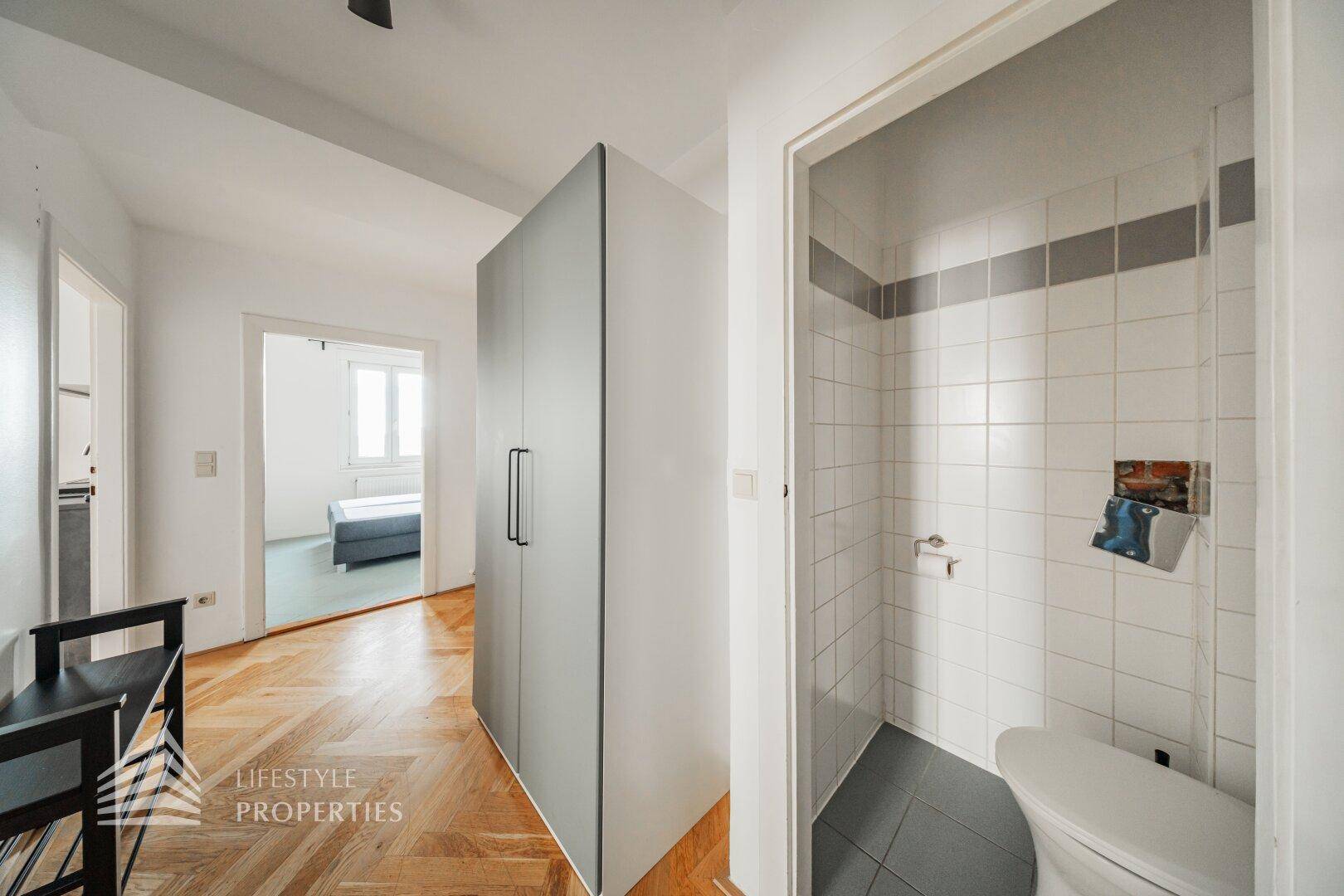 Separates WC mit Fliesenboden und Wandfliesen in Weiß und Grau.
