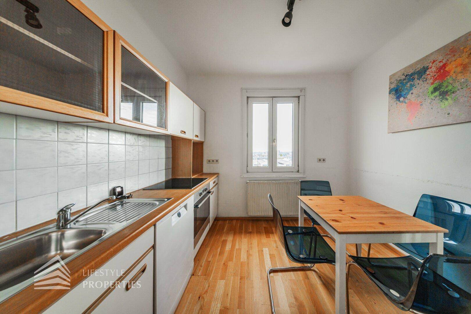 Funktionale Küche mit Holzarbeitsplatten, Essbereich und Fenster für Tageslicht.