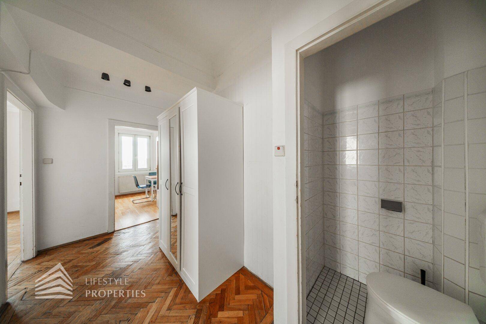 Flur mit Fischgrätparkett und Zugang zu einem separaten WC-Bereich.