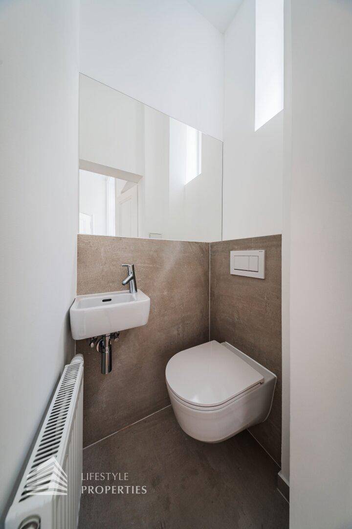 Modernes Gäste-WC mit wandhängender Toilette, kleinem Waschbecken und Heizkörper.