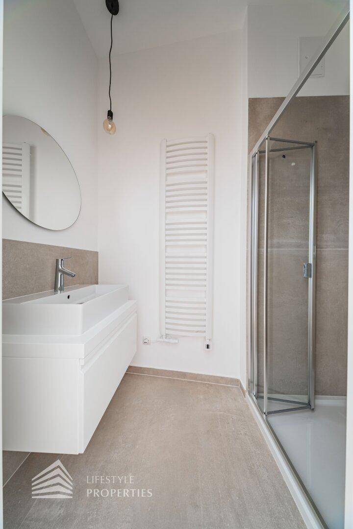 Modernes Badezimmer mit begehbarer Dusche, schwebendem Waschtisch und beheiztem Handtuchhalter.
