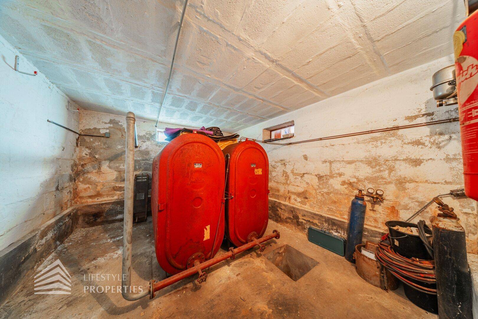 Lagerraum oder Keller mit großen roten Tanks und rohen Betonwänden.