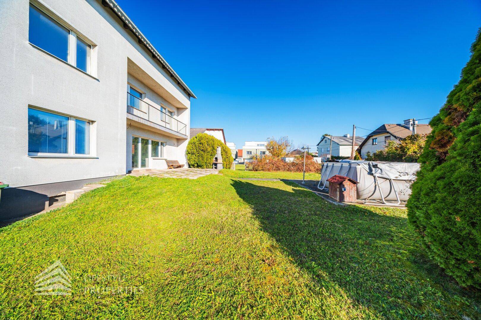Hinterhof mit Terrasse, Rasenfläche, Grillplatz und einem Aufstellpool im Hintergrund.